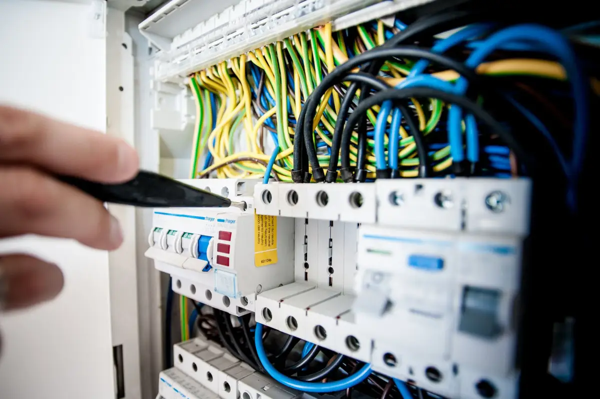 Hand working on breakers and wiring inside an electrical control panel feeding a gate operator