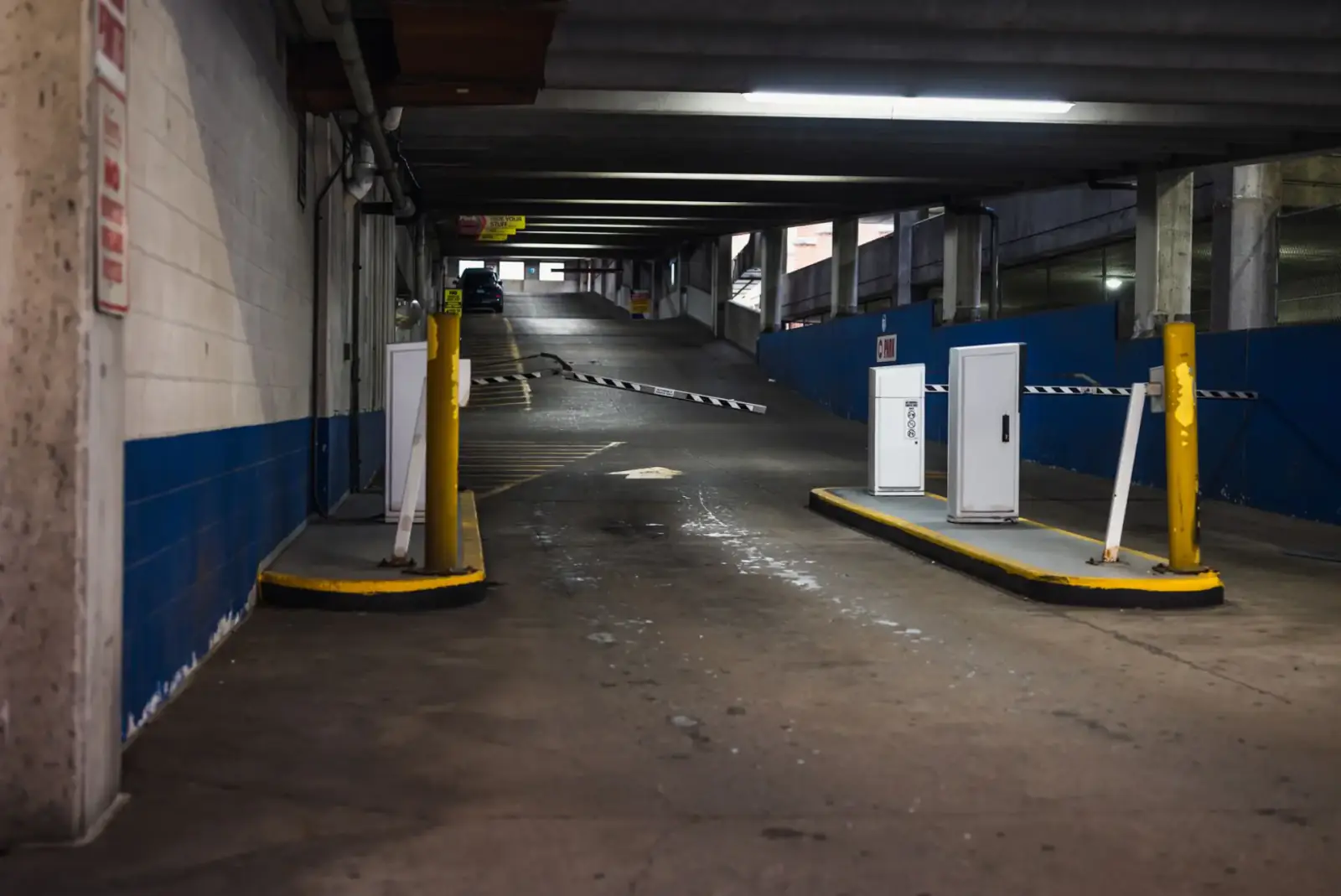 Automatic barrier arms and payment pedestals at the vehicle entrance to a commercial parking structure