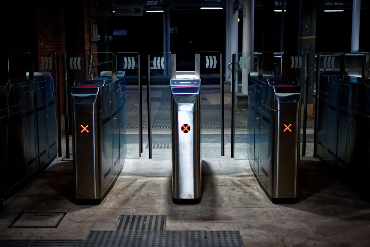 Bank of controlled-access speed gates with illuminated indicators at a building entrance