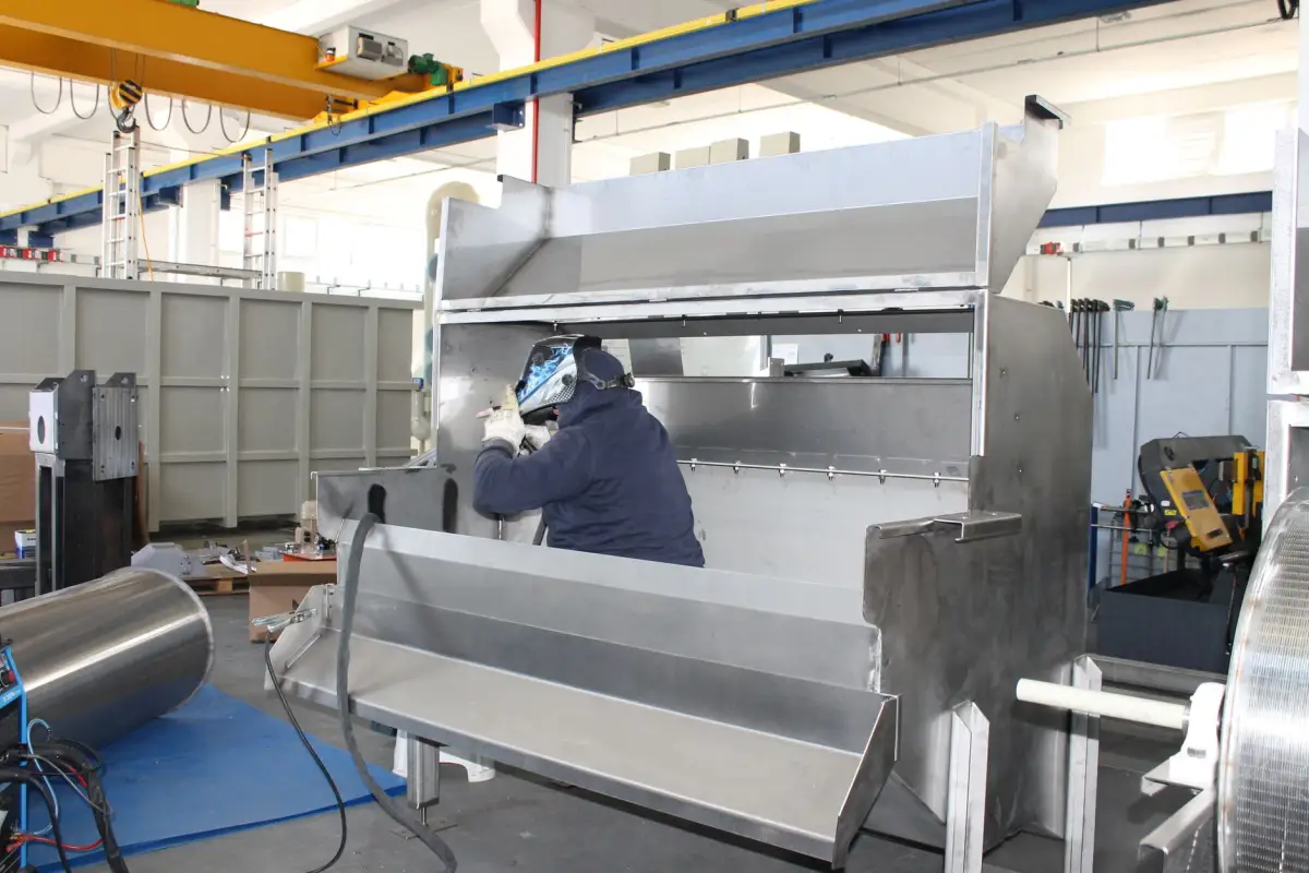 Fabricator welding large steel assemblies in a commercial metal fabrication shop