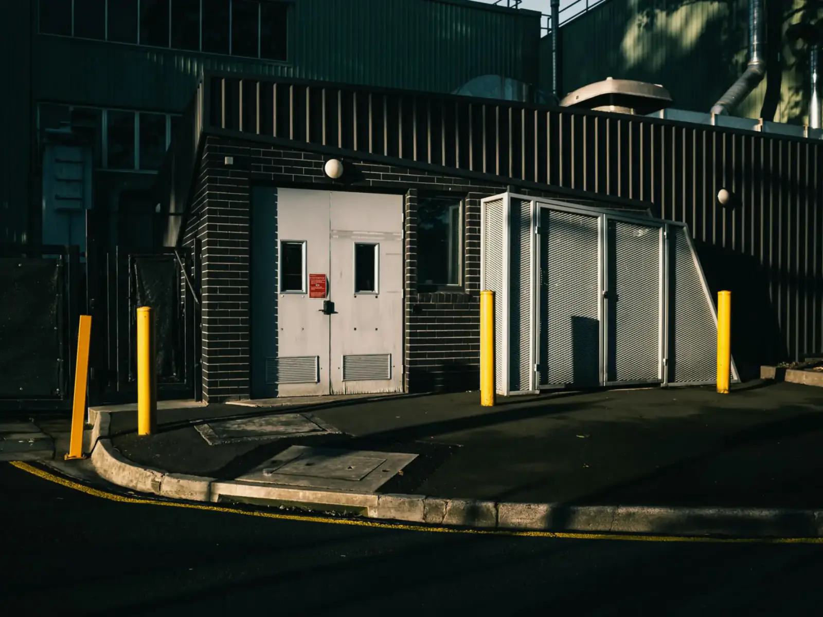 Guard building and metal gate with protective bollards at a controlled commercial site entrance