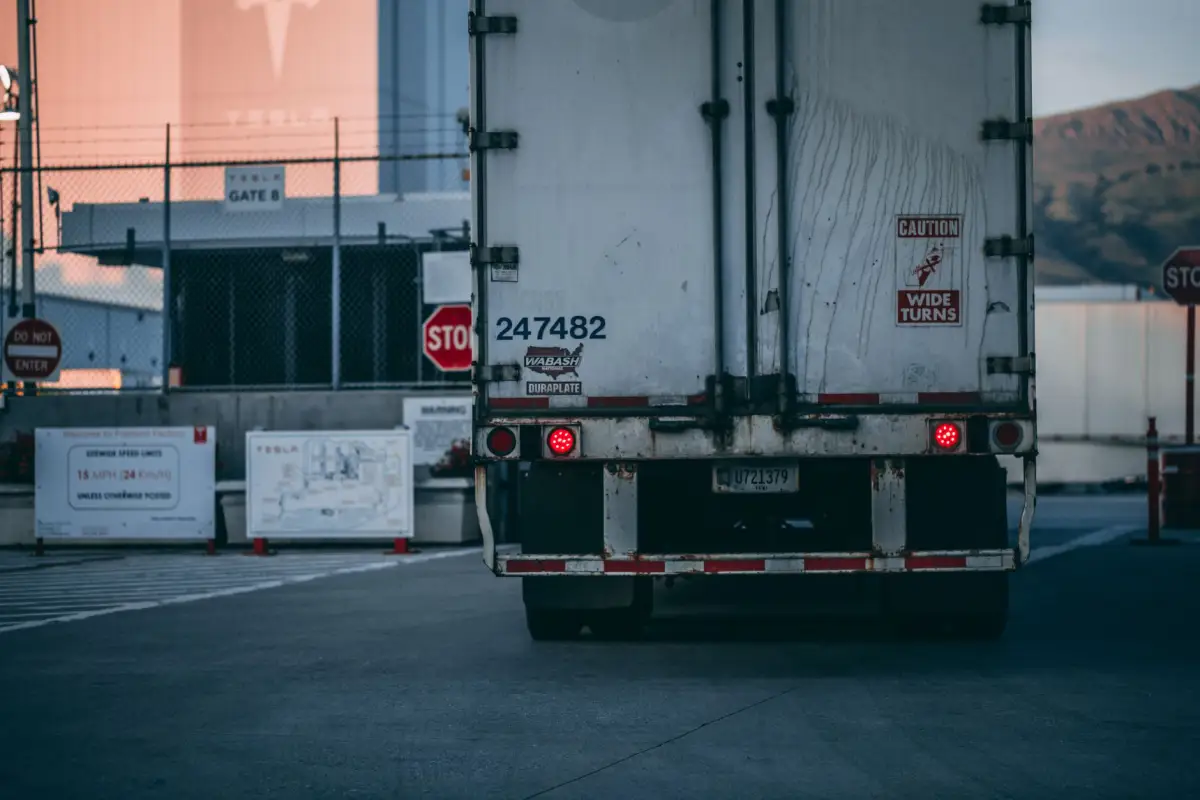 Truck passing through an open commercial yard gate at a fenced facility