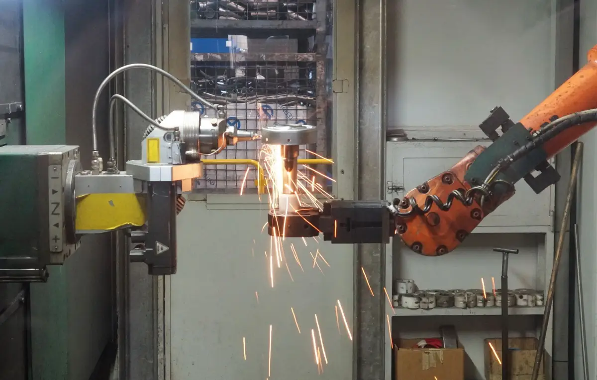 Robotic welding cell producing steel assemblies with sparks inside a fabrication plant