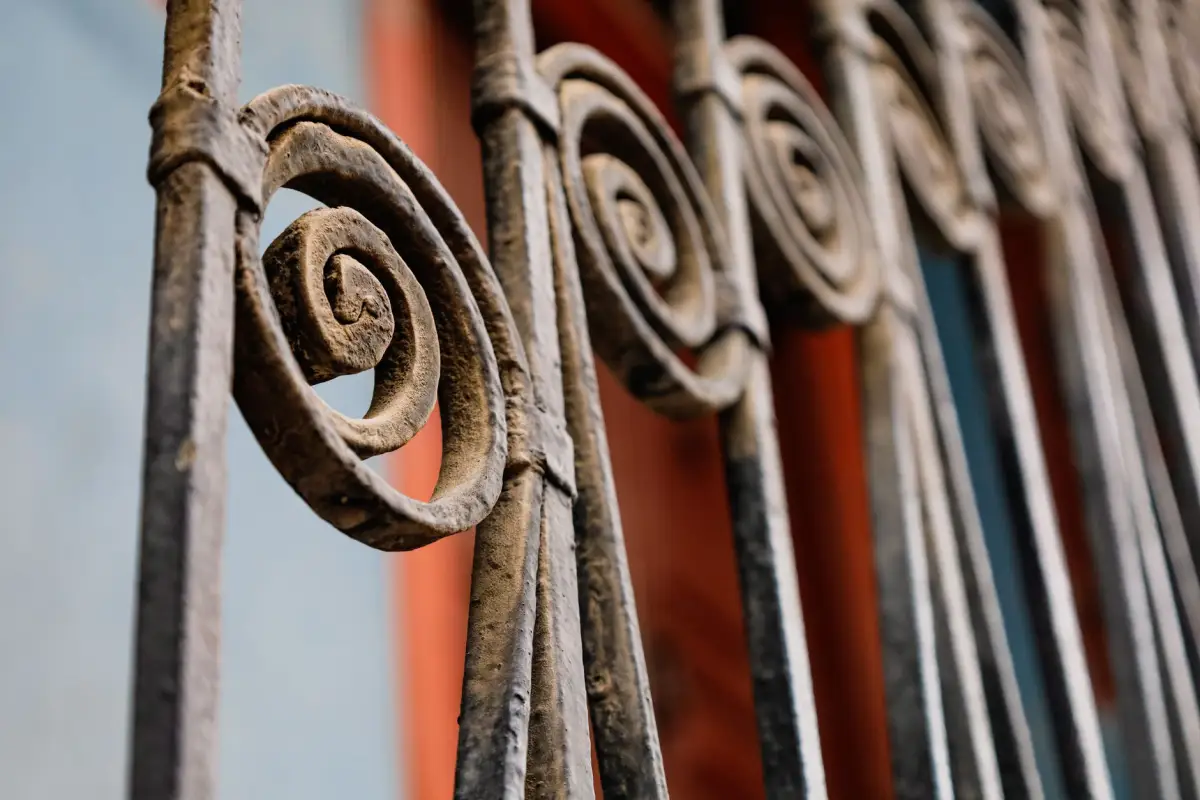 Close-up of forged iron scrollwork panels stacked on edge in a fabrication shop