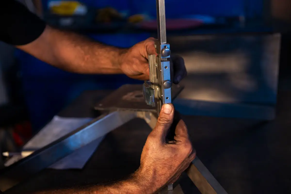 Fabricator's hands reading a vernier caliper against cut steel stock on a shop workbench