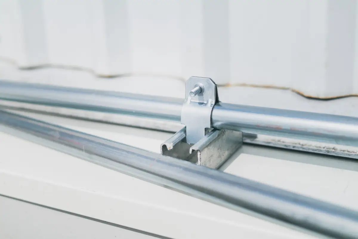 Galvanized conduit runs clamped to a structural channel during a gate operator power installation