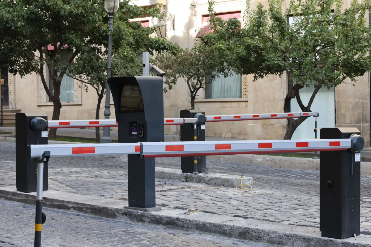 Pair of automatic barrier arms with control pedestals across a vehicle entry lane