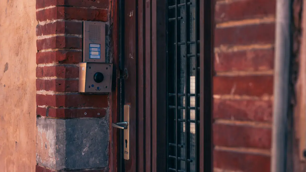 Gate entry keypad and intercom unit mounted on a brick pier beside a metal gate