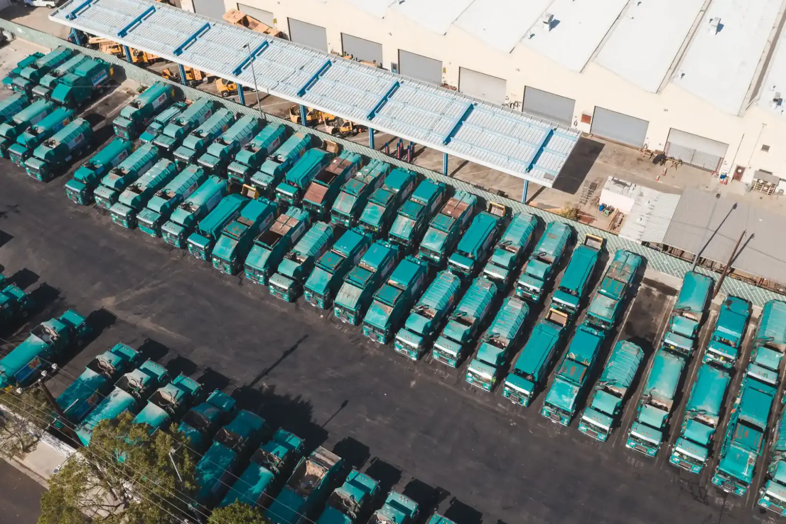 Aerial view of an industrial fleet yard with rows of trucks parked behind a controlled perimeter