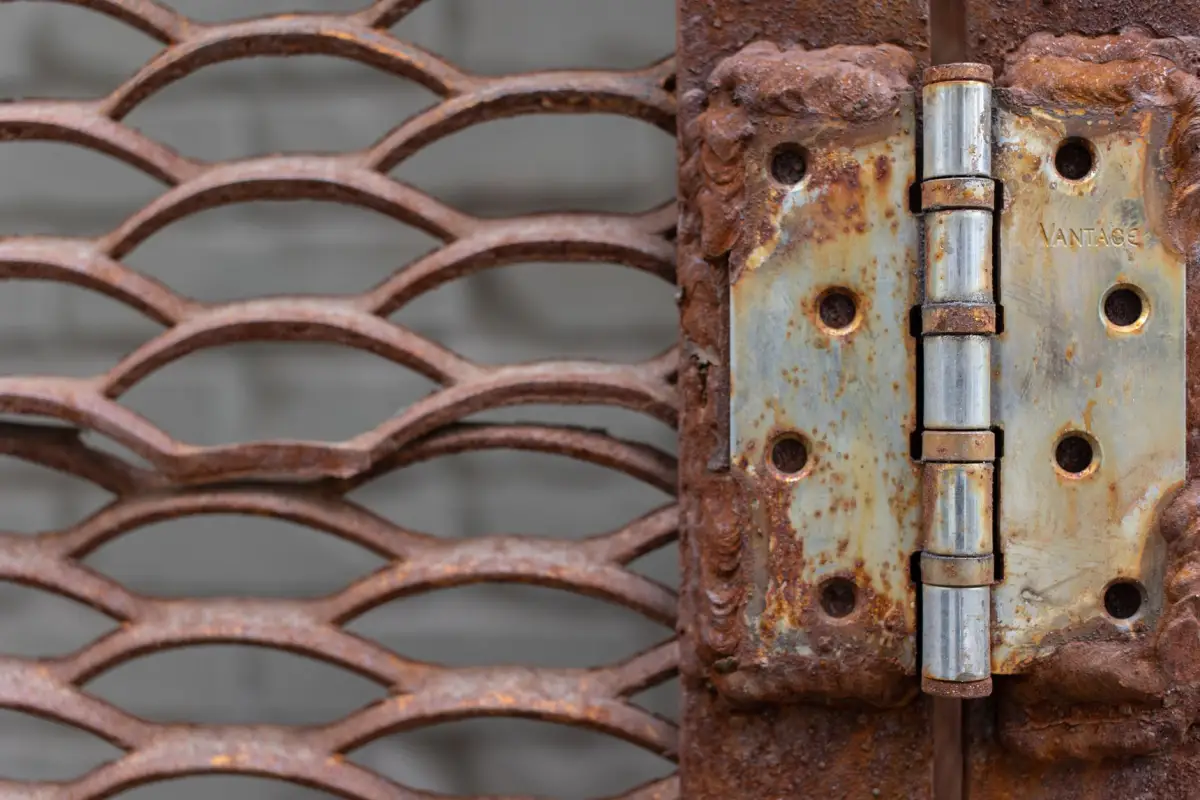 Heavily rusted hinge plate and pin on an expanded-metal gate frame