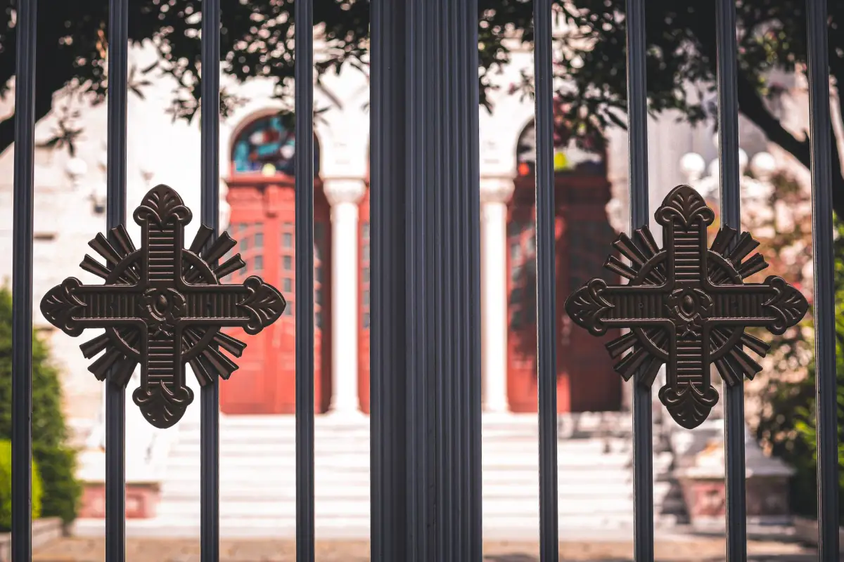 Close-up of cast rosette detail welded between the pickets of an iron pedestrian gate