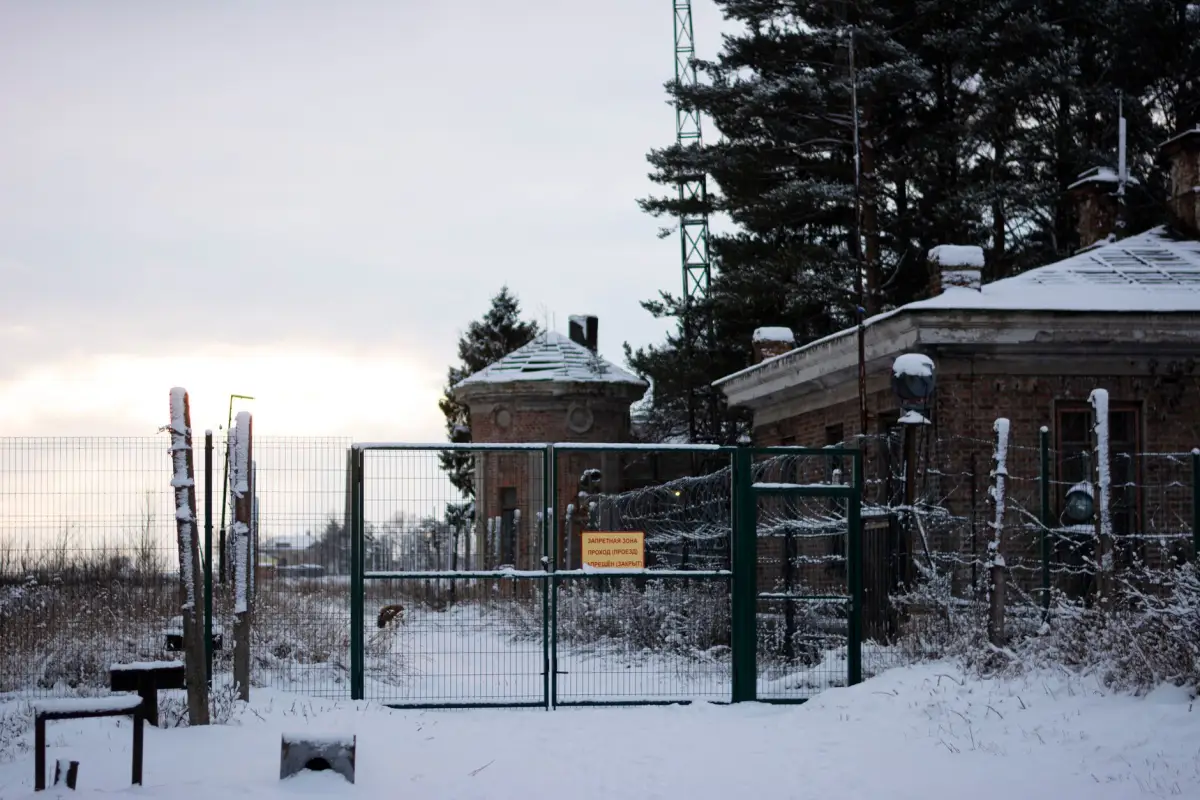 Mesh-infill perimeter security gate and fence line at a fenced compound under snow