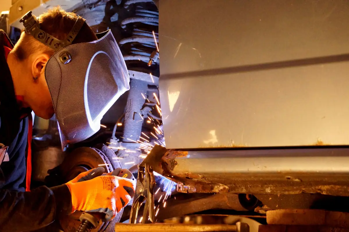 Welder in a hood and gloves welding a steel security gate frame with sparks flying