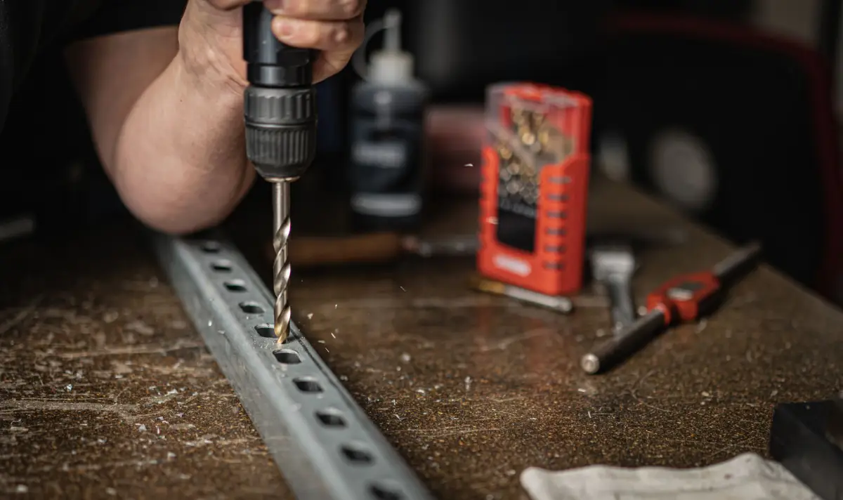 Drilling mounting holes through a steel channel section on a workbench during slide gate track fabrication